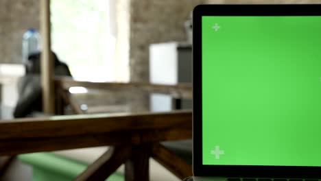 close moving shot of laptop display with chromakey in office with working people