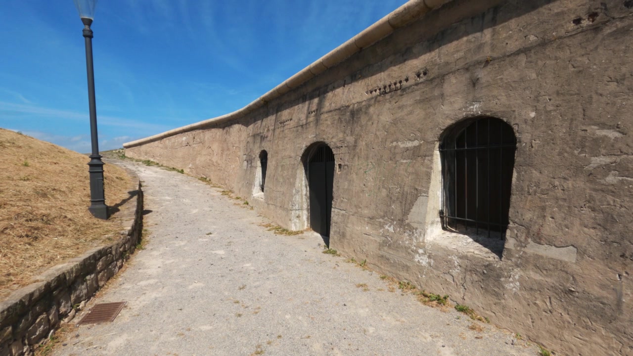 Sentiero pedonale lungo l'antica cinta muraria in pietra con portali ad arco presso la batteria di Santa Catalina a Gijon.