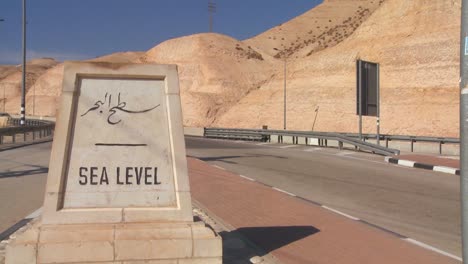 a road passes a sign indicating sea level near the dead sea in israel