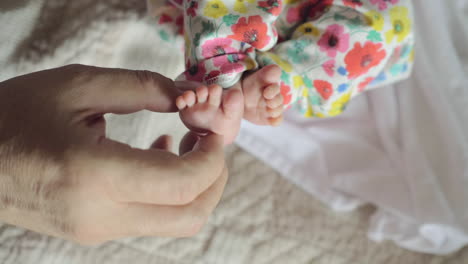 grandfather touching feet of newborn baby