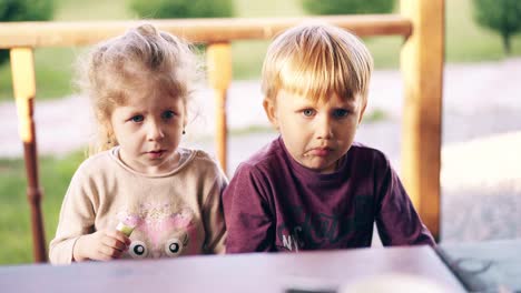 close-up children sit in the summer house and eat mom feeds them with vegetables