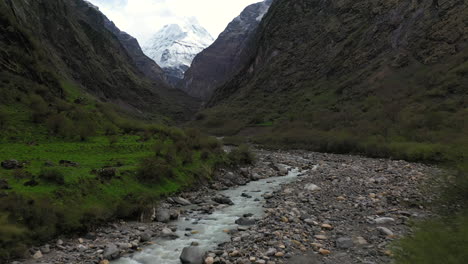 Revealing-aerial-drone-shot-of-a-white-water-river-and-a-large-mountain-side-in-the-Annapurna-mountains,-Nepal