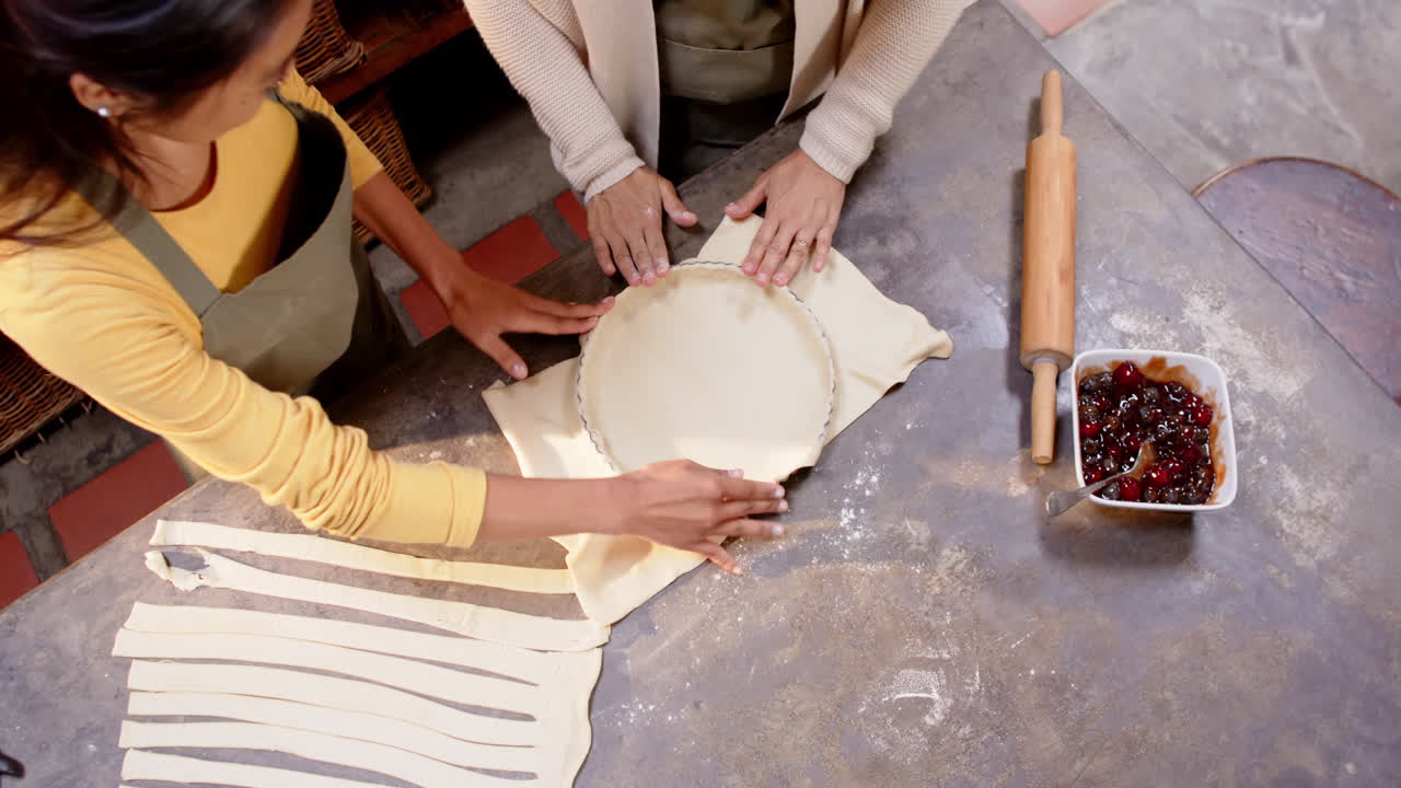 Multiracial grandmother and young woman preparing pie crust together in cozy kitchen, at home