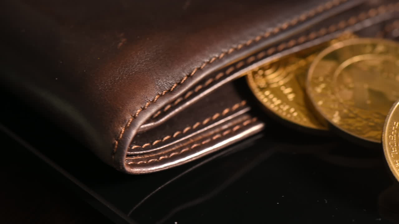 Close view of physical crypto coins spilled out of the wallet, golden Bitcoin