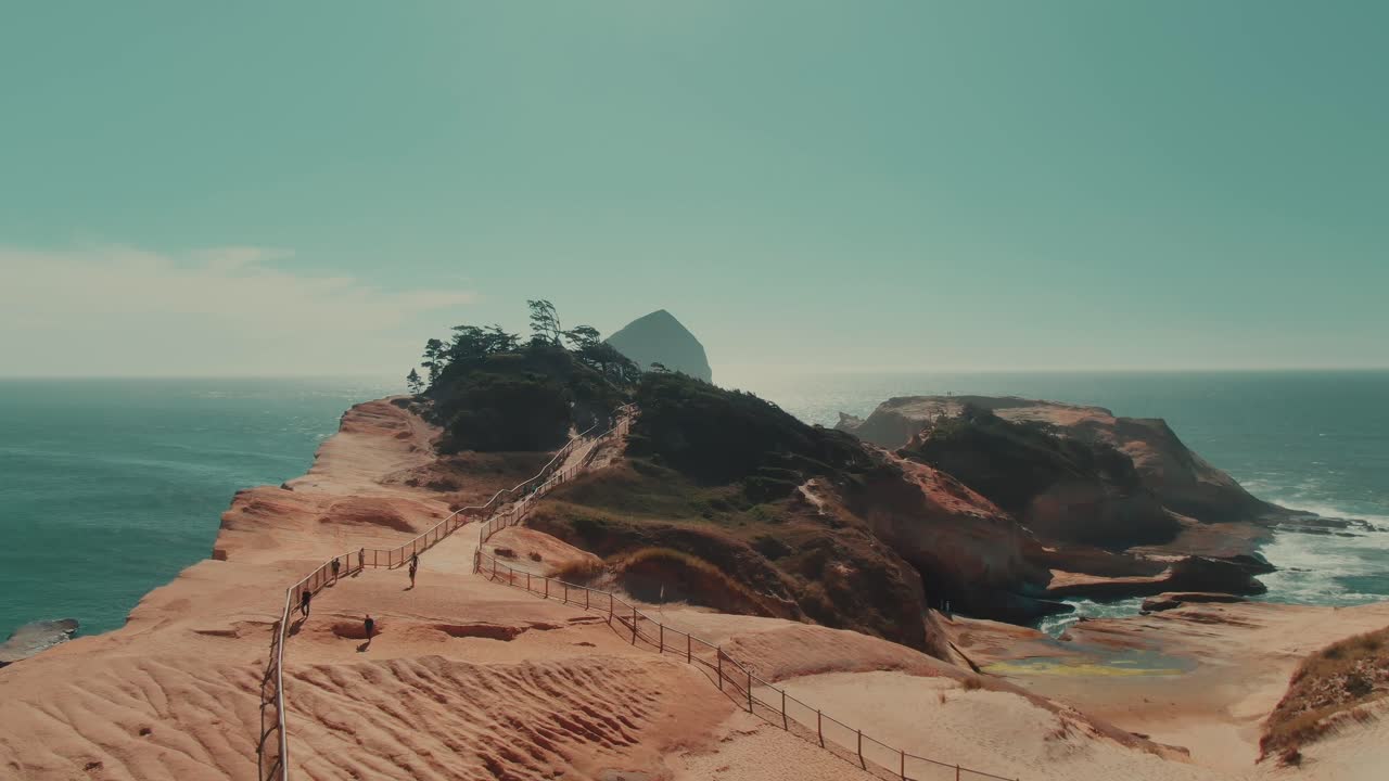 4k Aerial rocky sandy coast with big rock in ocean in background