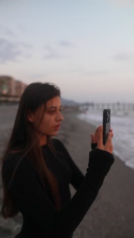 teenage girl taking a picture on the beach at sunset