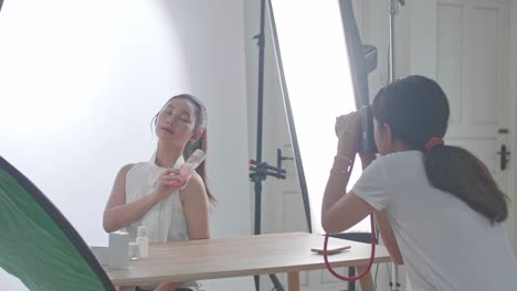 behind the scenes on photo shoot: beautiful asian model poses for a photographer, she takes photos with professional camera