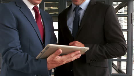 Smiling-businessmen-using-tablet-