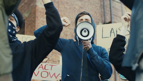 african american man yelling on a loudspeaker in a protest with multiethnic group of people in the street