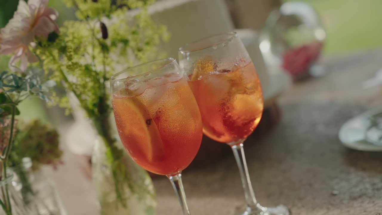 Dos aperol spritz fríos servidos con hielo y decoración cítrica