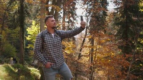 hombre tomando una selfie en el bosque de otoño