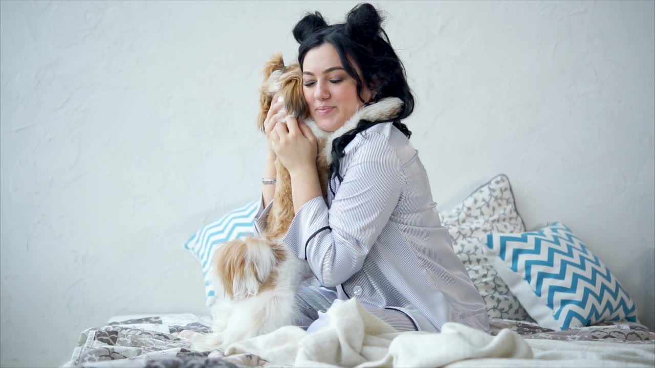 Woman cuddling with her Shih Tzu dog in bed