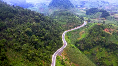 Toma-Aérea-De-Vehículos-Que-Viajan-Por-Una-Peligrosa-Carretera-De-Montaña