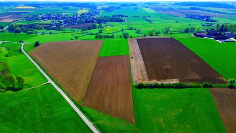 aerial view of diverse agricultural fields with varied crop growth and scenic countryside