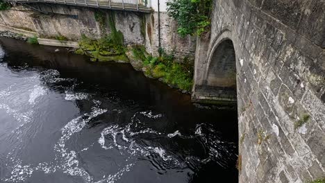 river flows under historic stone bridge