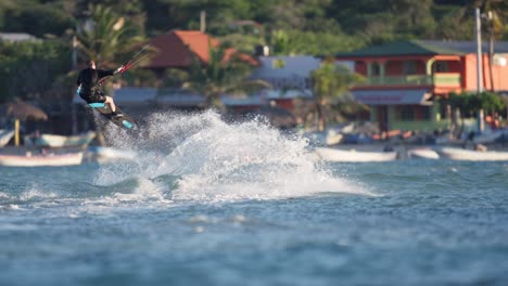 young man makes trick jump on kiteboard by carribean sea coast, slomo