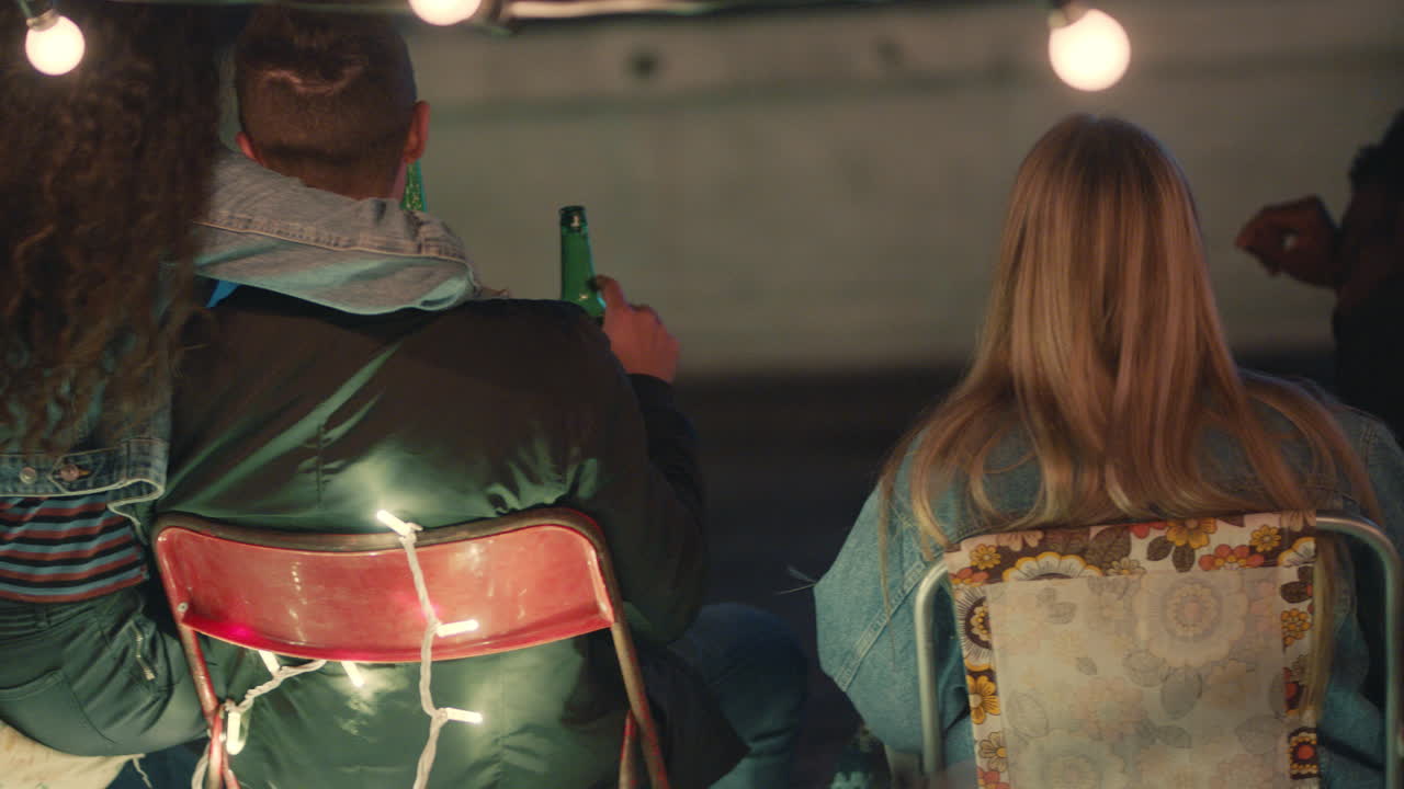 grupo de amigos viendo una película en el cine de la azotea pasando el rato juntos disfrutando de una fiesta de reunión de fin de semana en la ciudad urbana por la noche