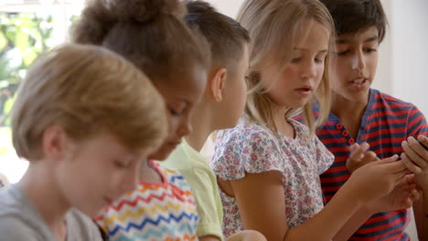 group of children sit on window seat and use technology