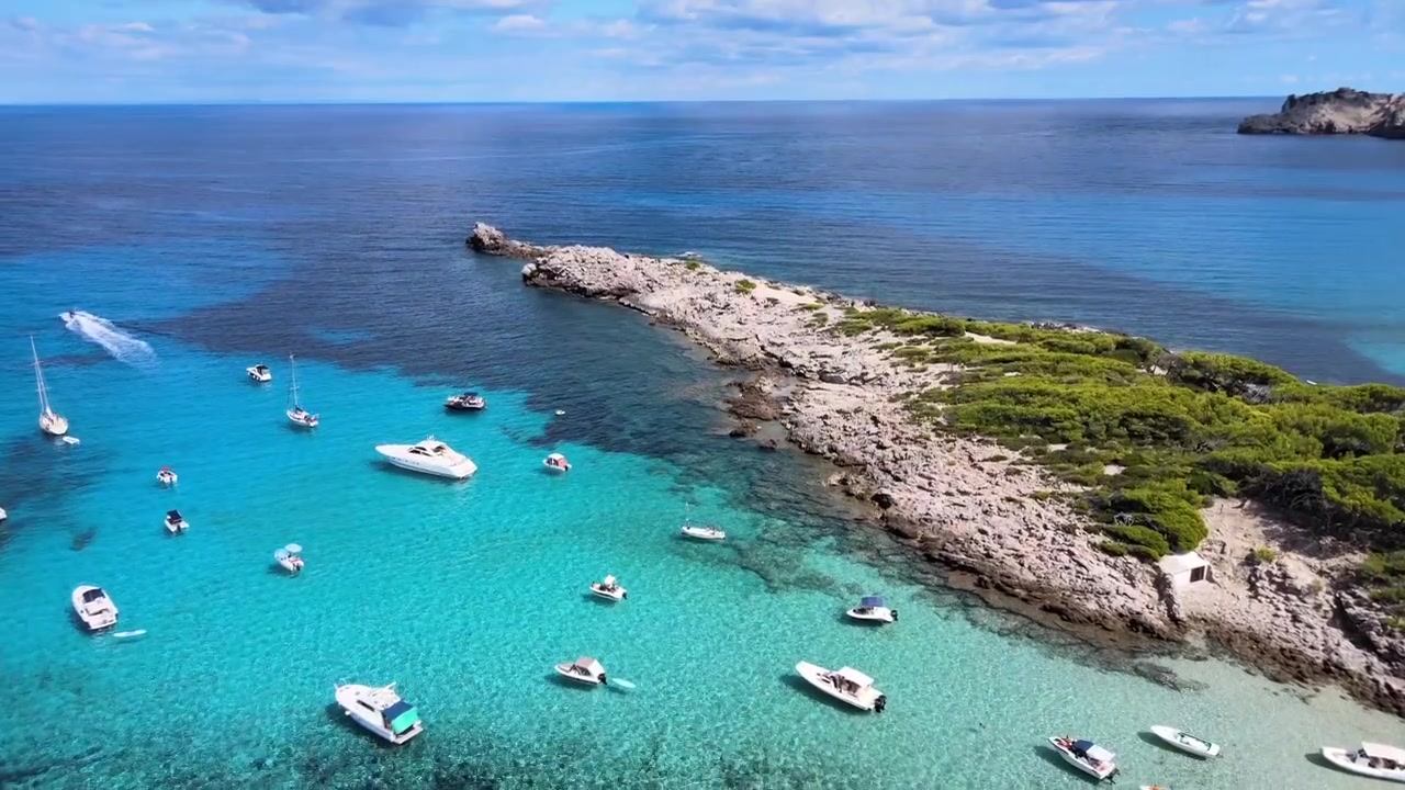 Goditi una giornata tranquilla a Cala Agulla a Cala Rajada, Maiorca. Le acque azzurre sono punteggiate da barche, mettendo in mostra la bellezza naturale e l'atmosfera serena della regione.