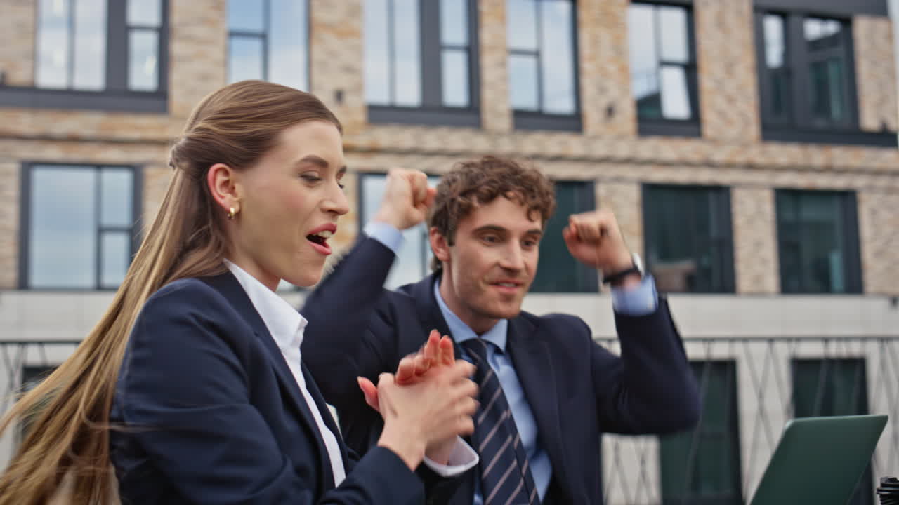 Overjoyed colleagues celebrating victory reading at laptop on terrace closeup