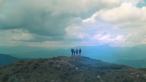 los cuatro excursionistas están de pie en la cima de la montaña