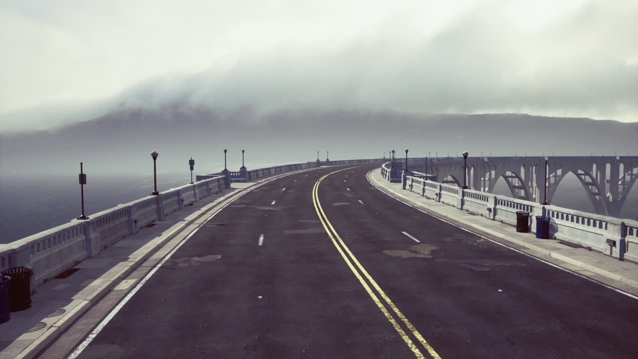 Foggy morning on a winding road at a coastal bridge in a serene landscape