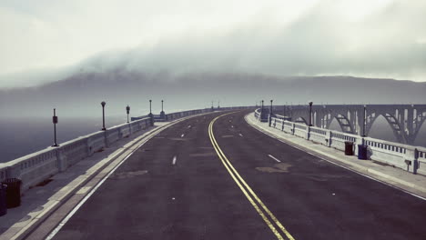 foggy morning on a winding road at a coastal bridge in a serene landscape