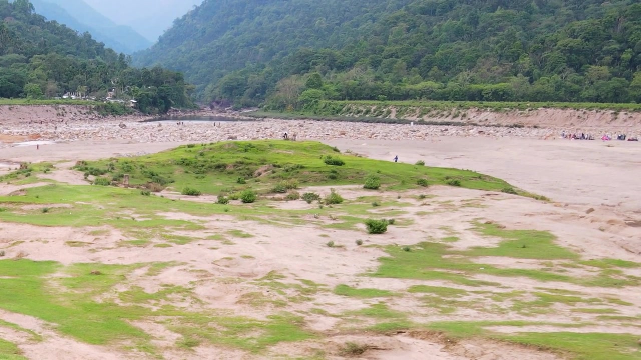 Cảnh quay trên không sông Piyain khô cạn tại Bichanakandi, với những bãi cát lộ thiên và hoạt động khai thác đá, thể hiện vấn đề môi trường và biến đổi khí hậu.