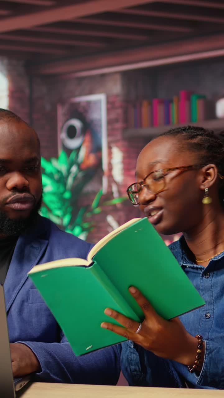 Focused Woman Reading Book and Man Working on Laptop