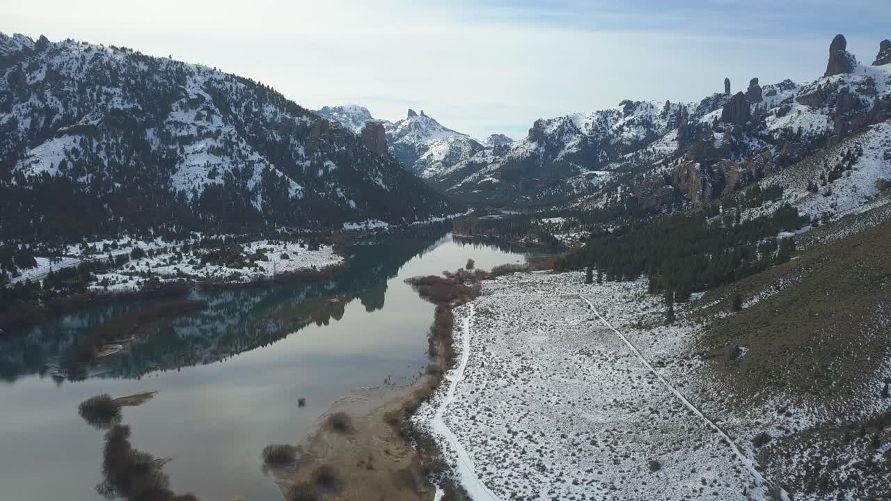카메라는 해가 지는 바위산으로 둘러싸인 거울 같은 강 위로 천천히 움직입니다.