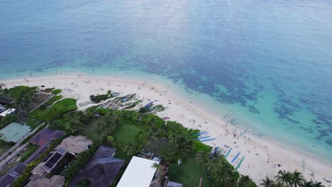 drone footage panning slowly to the left of lanikai beach on the island of oahu whith white sand beach and clear water showing the reefs on the ocean floor