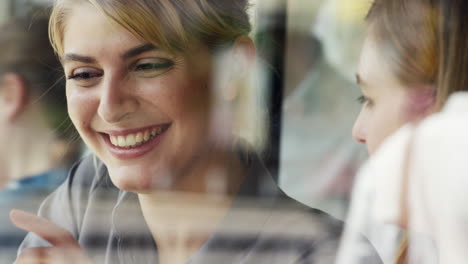 Dos-Mujeres-Usando-Una-Tableta-Digital-Bebiendo-Café-En-La-Cafetería