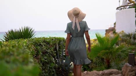 stunning video of a caucasian girl wearing a knitted hat and beautiful green dress walking to the beach de la pillisseta and admiring the breathtaking view. daytime footage under sunny skies.