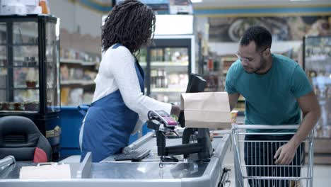 cheerful young man walking with shopping cart to counter