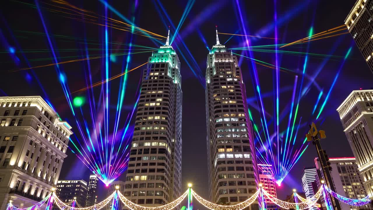 Vibrant light display illuminating twin skyscrapers at night, showcasing dynamic laser beams and colorful patterns, creating a mesmerizing urban spectacle