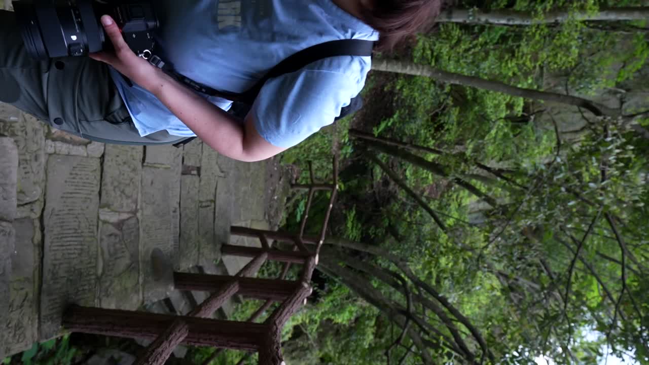 tomada vertical de un turista con una cámara caminando por un camino forestal hacia la aldea de huangshi, china