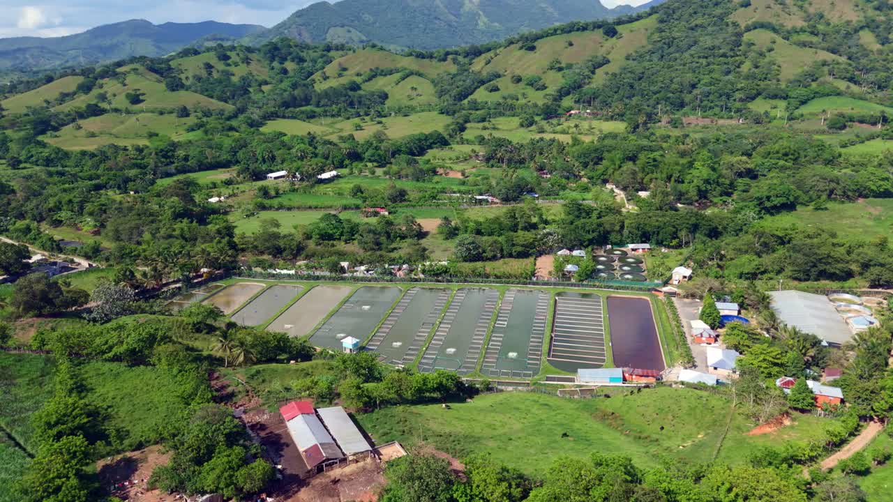 Picturesque green mountain landscape of Bonao Town with Aquacultural Hatchery waters in the valley. Aerial wide shot. Dominican Republic in summer.