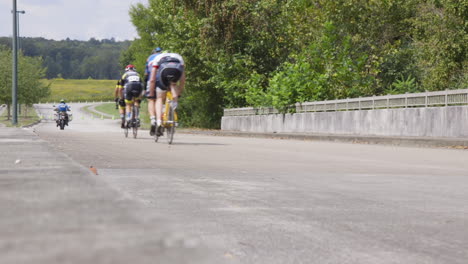 Das-Führungsmotorrad-Und-Mehrere-Tandemfahrräder-Radeln-Während-Eines-Para-Cycling-Rennens-An-Der-Kamera-Vorbei