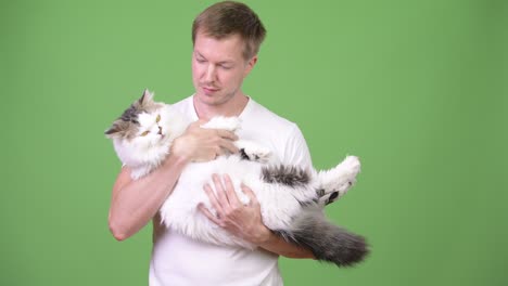 joven feliz y guapo con un gato persa