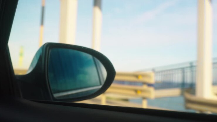 Rear view mirror with defocused background, driving on the coast side