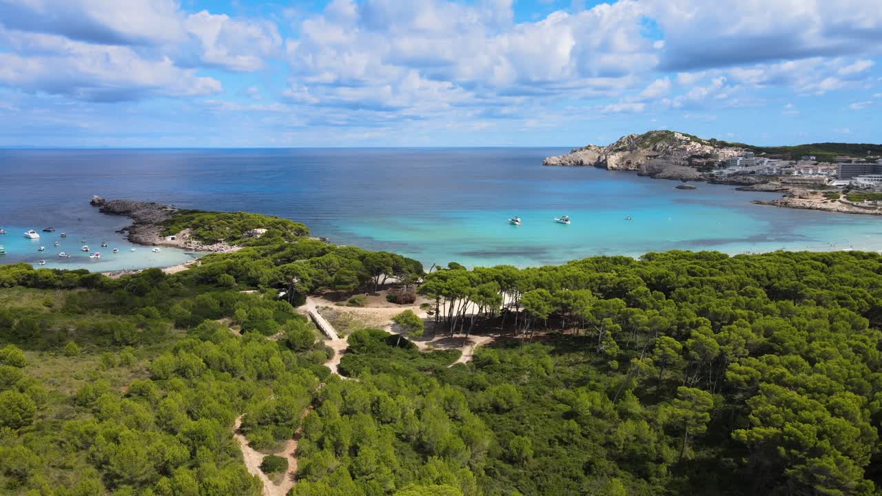 sea testigo del impresionante paisaje de cala agulla en cala rajada, mallorca, con aguas azules claras, exuberante vegetación y barcos navegando a lo largo de la costa. un lugar perfecto para la relajación y la aventura.