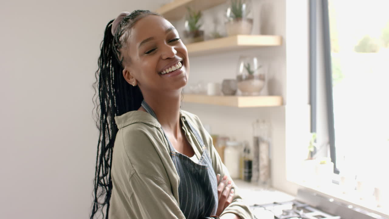 African American young woman standing in kitchen, smiling