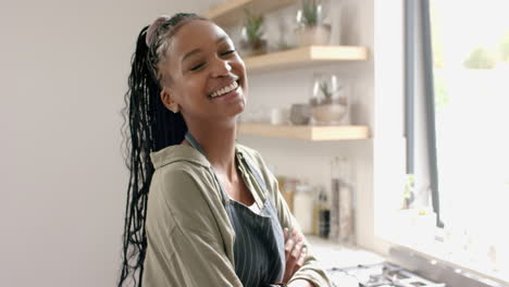 African-American-young-woman-standing-in-kitchen,-smiling