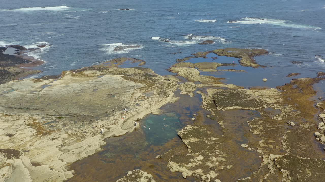 Aerial dolly of a tidal pool on the west coast of Ireland, capturing swimmers enjoying a beautiful day. Slow motion
