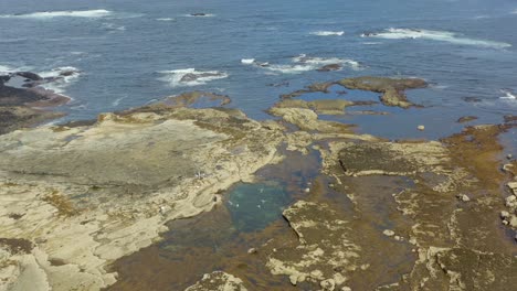 aerial dolly of a tidal pool on the west coast of ireland, capturing swimmers enjoying a beautiful day. slow motion