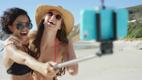 dos amigos tomando selfies en la playa usando un palo de selfie