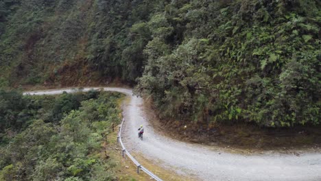 aerial: ciclista monta en bicicleta en el famoso camino de la muerte de yungas en bolivia mtns