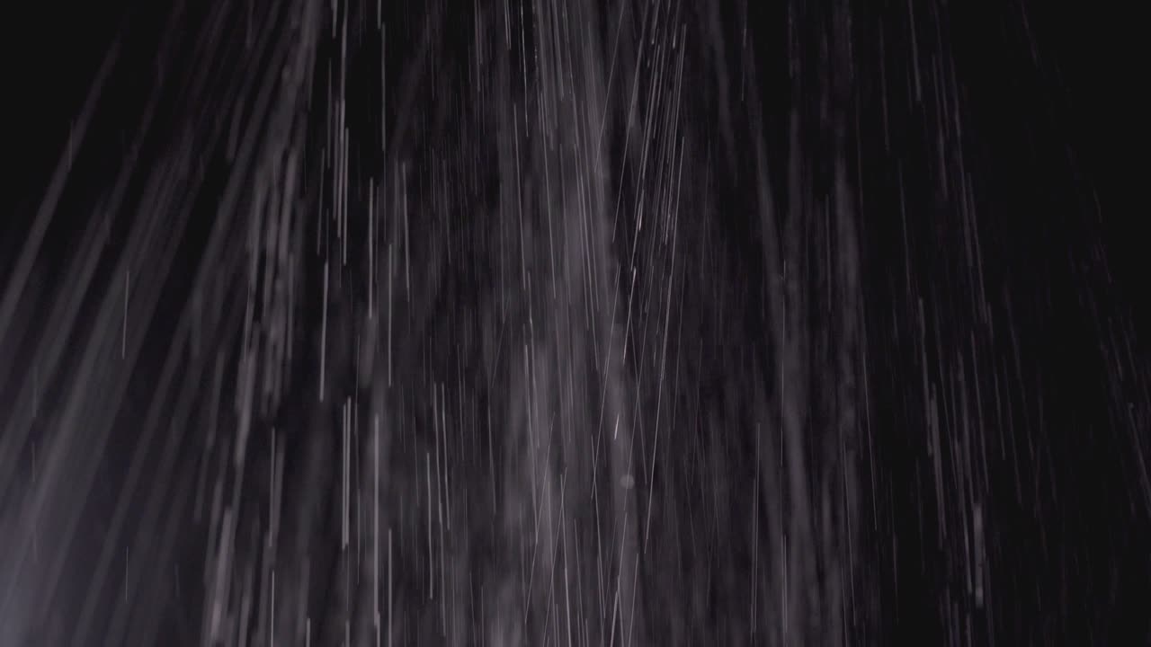 Jets of water pouring on a black background. The rain is pouring down, texture