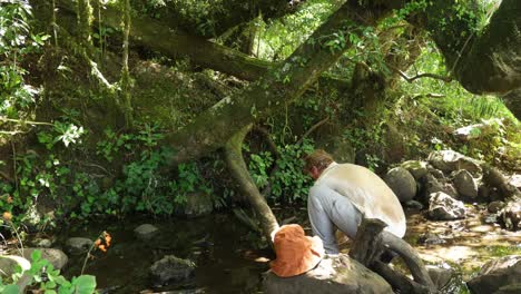un bushman occidental se enfría en un pequeño arroyo de montaña mientras hace senderismo en áfrica oriental