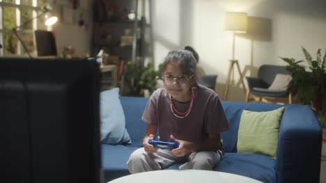 young girl playing video games on a couch at night
